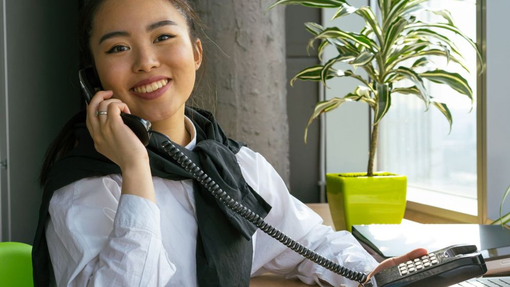 A smiling coordinator on the phone at her desk