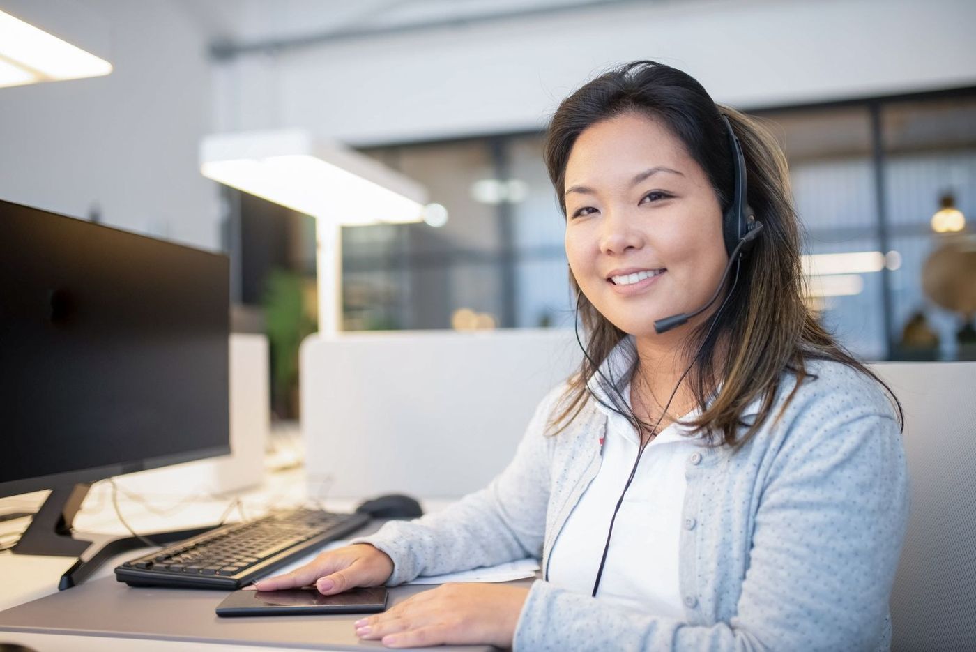 A coordinator with a headset smiling at her desk